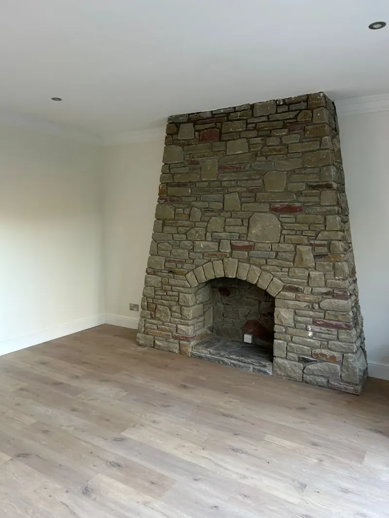 Completed living room with stone fireplace and oak flooring by JRD Construction