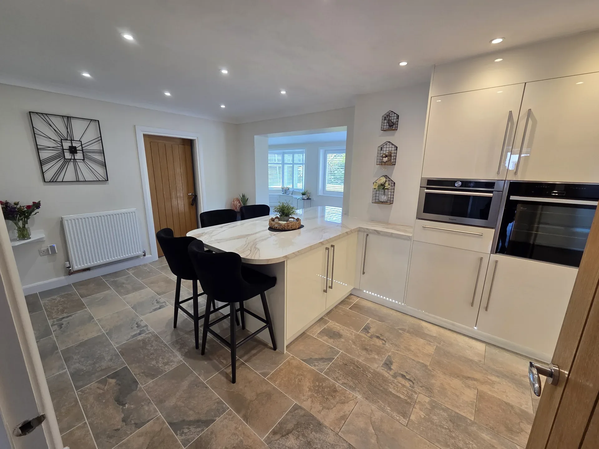 White gloss kitchen with island and built-in ovens by JRD Construction Bridgend